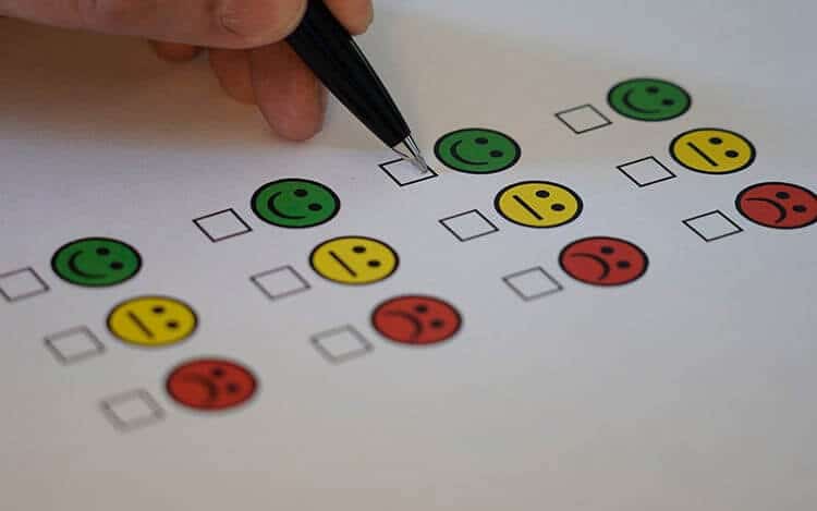 Rating Card Image with hand holding a pen with check boxes for happy, mediocre and unhappy faces.