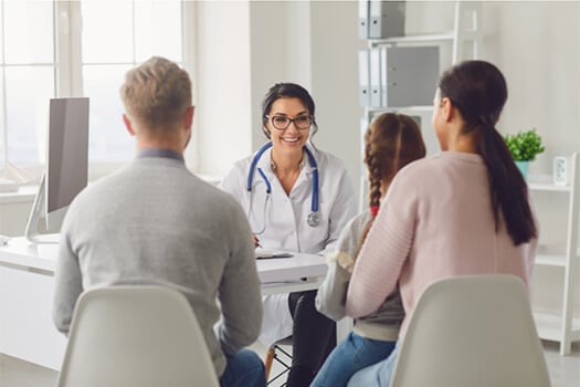 Family doctor converses with mixed family in office setting
